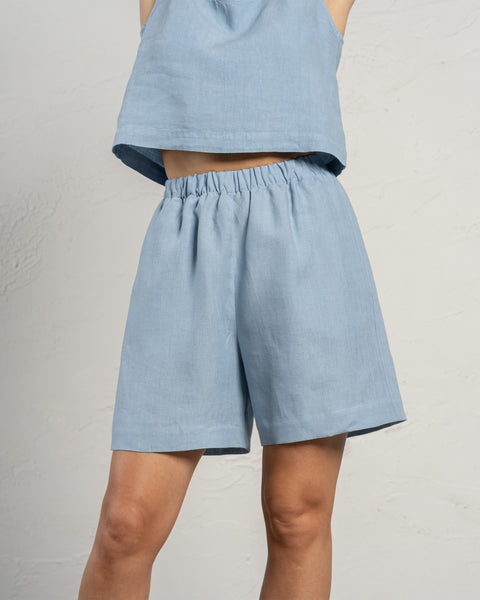 Linned Bermudashorts i farven skyblå. Højttaljede, længere shorts med lommer og elastik i taljen.
