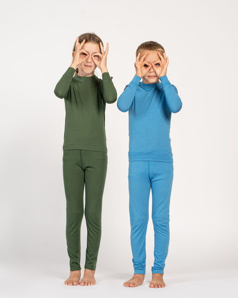To børn iført grønne og blå pyjamasæt på hvid baggrund