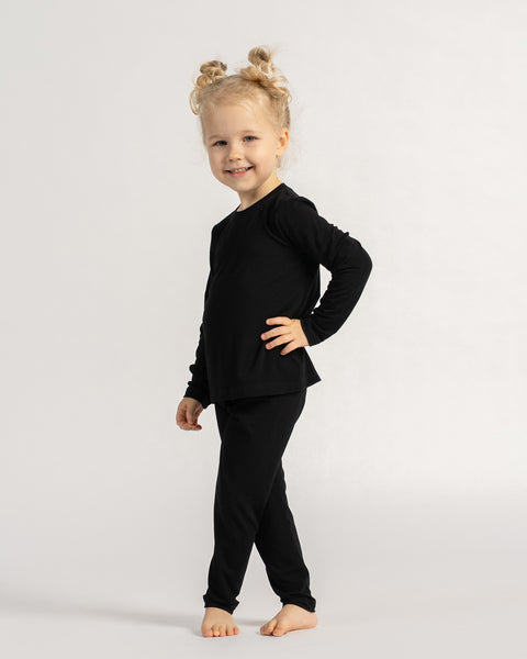 Barn står iført sort bambus langærmet skjorte og leggings, der viser fleksibel pasform og daglig komfort.