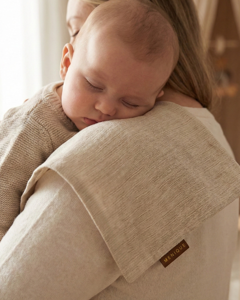 Natural linen baby burp cloth on mother’s shoulder while holding sleeping newborn, soft breathable muslin for gentle skin care