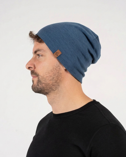 Man wearing denim blue merino wool liner beanie, soft breathable wool hat suitable for hiking, running, and daily wear.