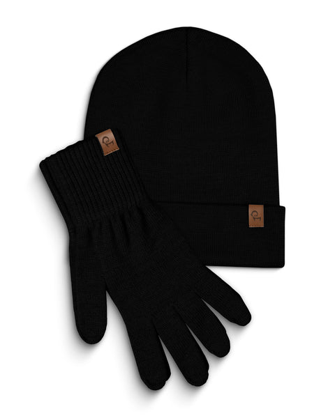 Black knitted beanie and a pair of matching gloves are laid flat against a white background. Both the beanie and each glove have a small, rectangular brown leather tag with a menique logo on them. The items are slightly overlapping, with the beanie positioned above and to the left of the gloves.