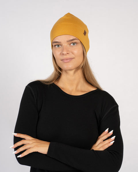 Woman posing with arms crossed, wearing yellow merino wool beanie.