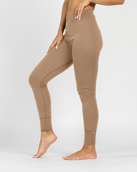 Kvinde iført beige leggings i merinould på hvid baggrund