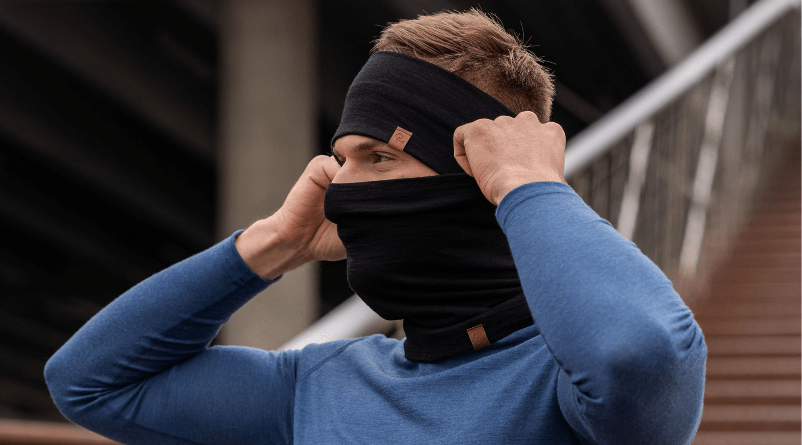 Man outdoors wearing dark green merino wool gaiter and beanie.