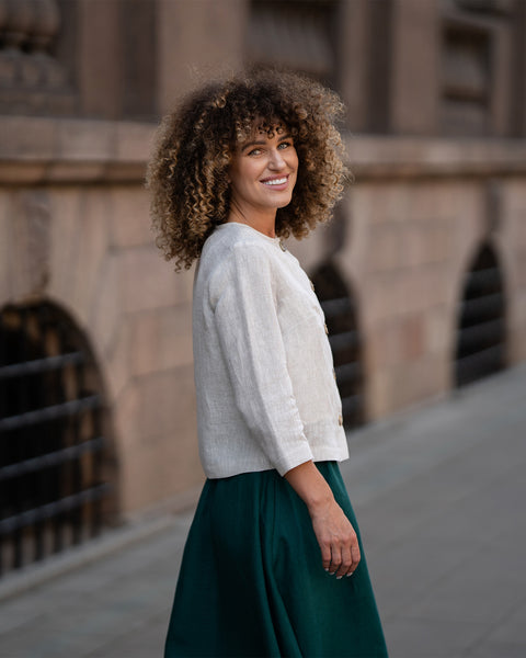 En model iført en naturlig beige hørjakke Alice med knapper, der har en afslappet pasform, 3/4-lange ærmer og et enkelt design
