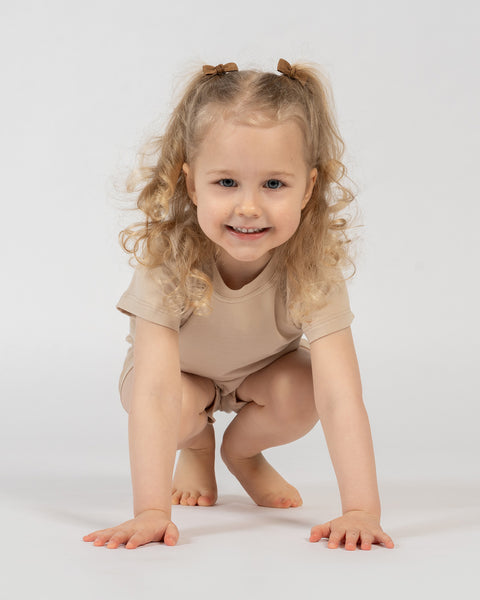 Kids beige bamboo clothing set – girl squatting in soft breathable t-shirt and shorts