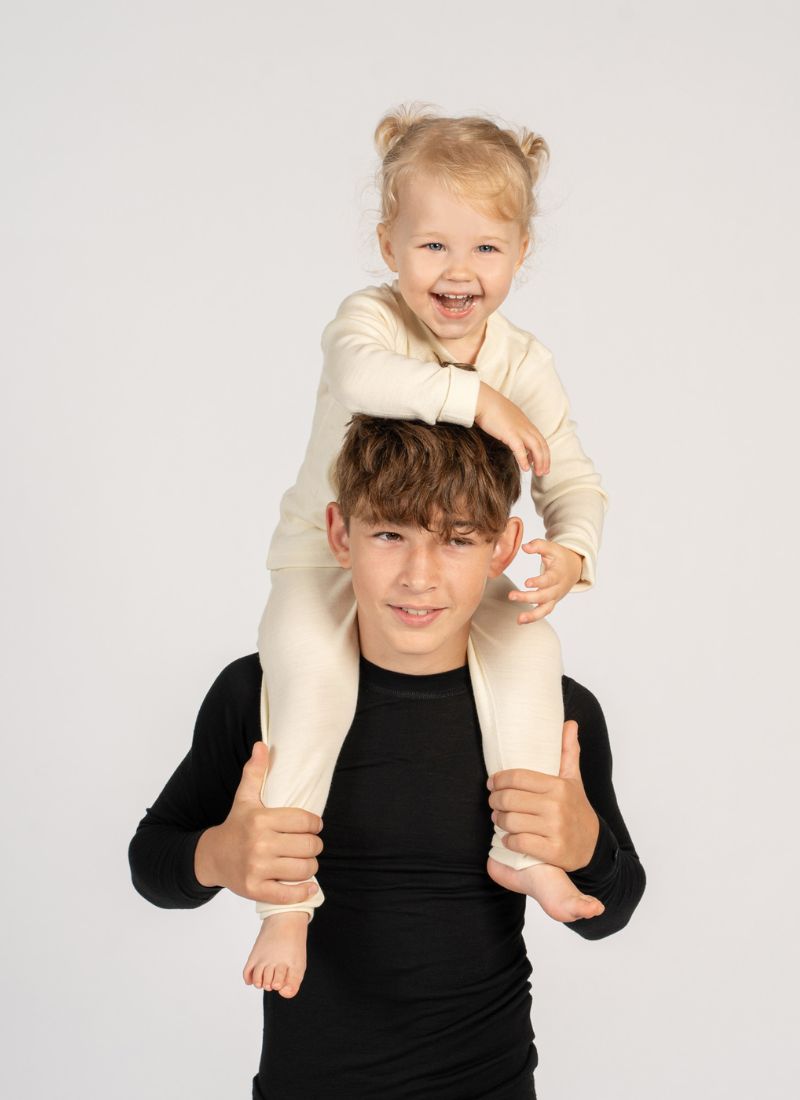 Child on another child's shoulders against a plain background