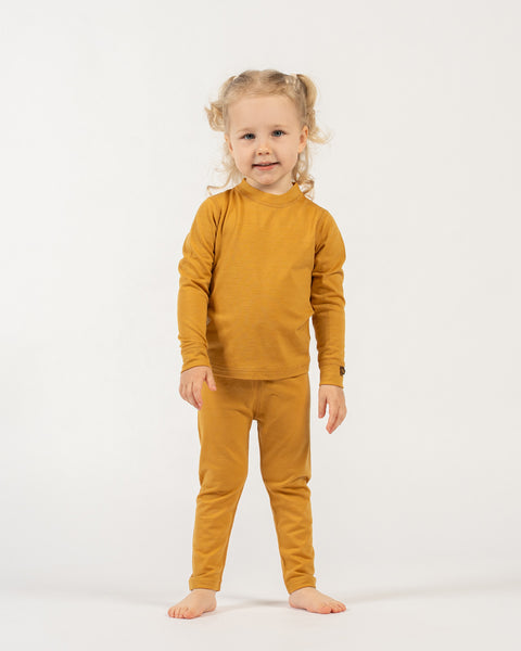 Child wearing a menique merino wool  kids' yellow outfit on a white background