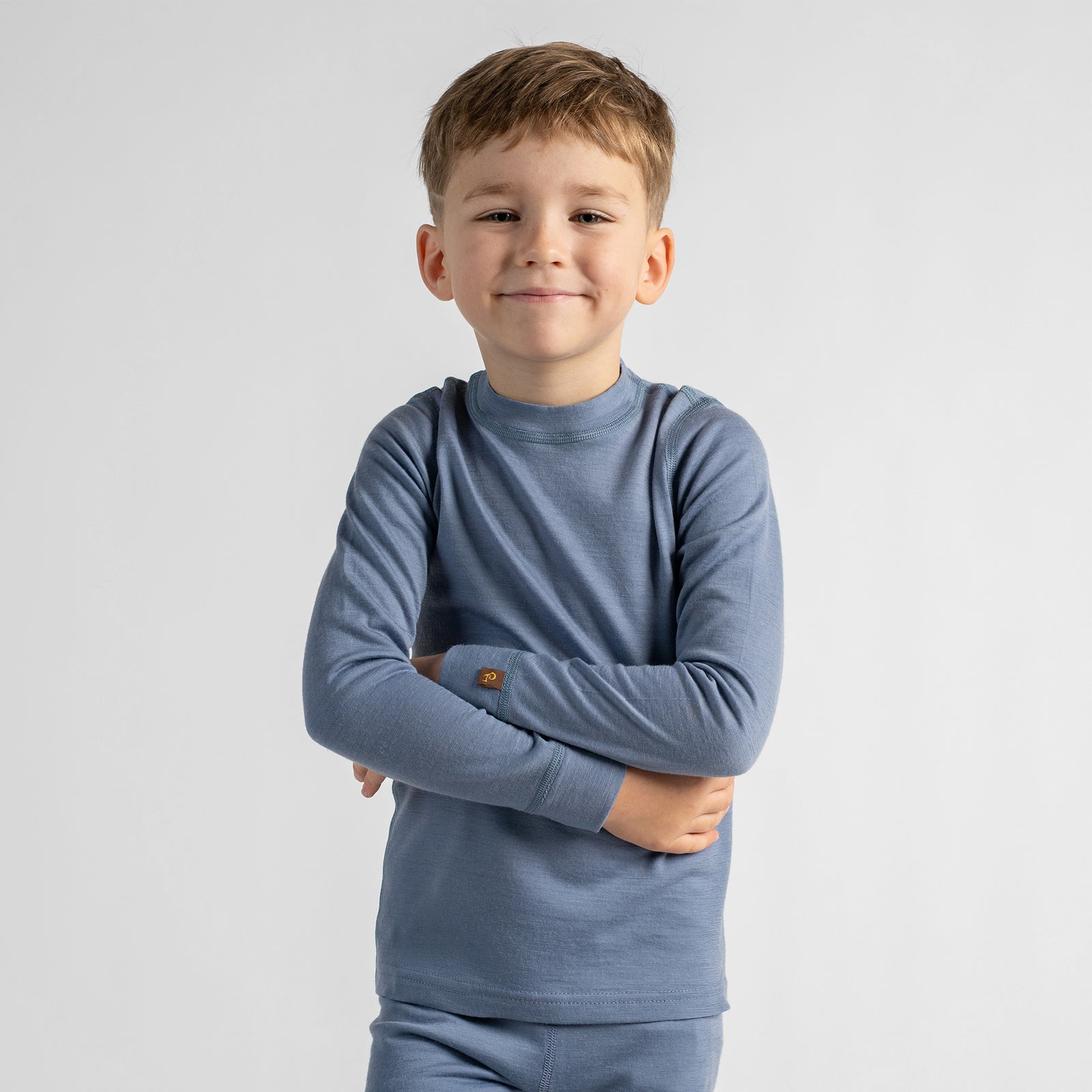 A front-view product shot of a children's long-sleeved fitted top in a heathered dusty blue color, displayed flat against a pure white background. The shirt features a simple crew neckline and cuffed sleeves.