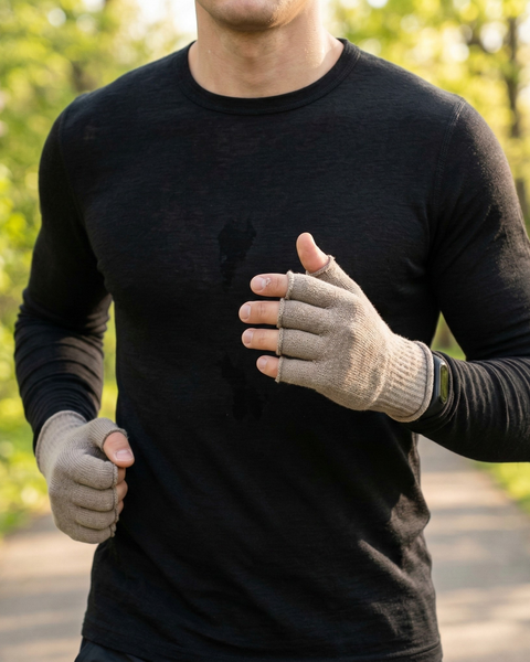 Man running outdoors wearing lightweight merino wool fingerless gloves and black merino base layer, breathable spring running gloves for temperature regulation and moisture control