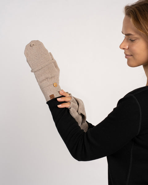 Nærbillede af en models hænder, der viser en cremet-beige vendbar vante og en fingerløs handske sammen (vanteklap synlig).