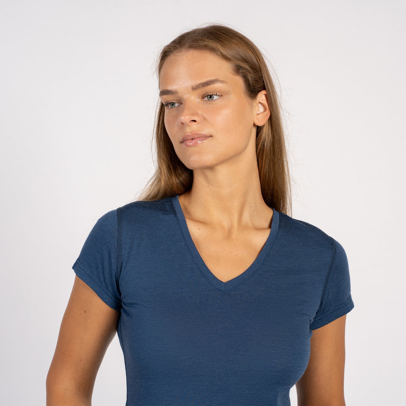 Kvinde smilende i en denimblå Merinould T-shirt med V-hals og korte ærmer.