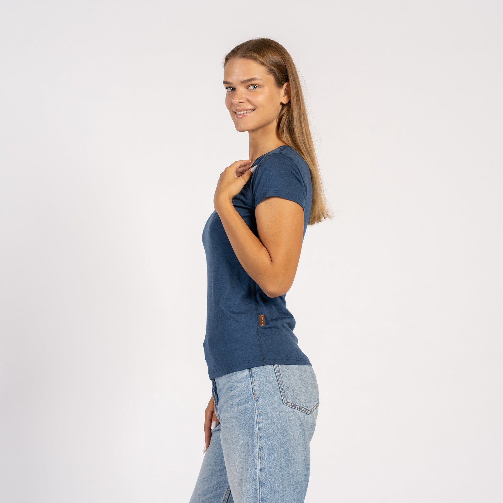 Kvinde smilende i en denimblå Merinould T-shirt med V-hals og korte ærmer.