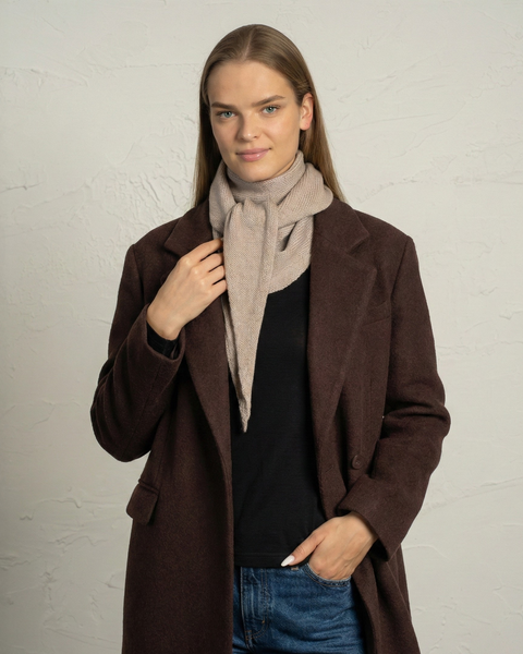 Kremet beige merinouldstrikket bandanasjal viklet om en kvindes hals.