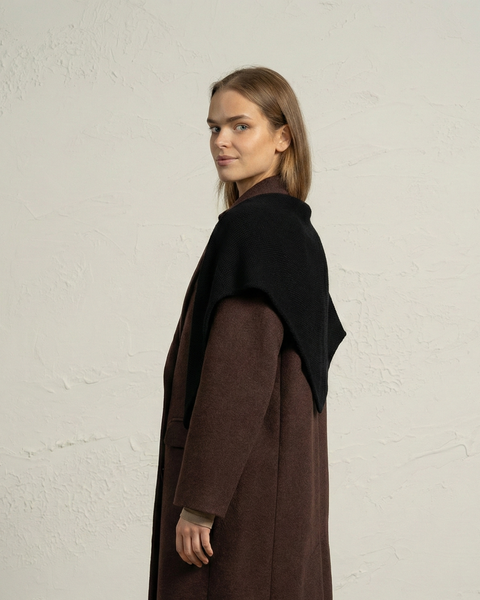 Sidet udsigt af kvinde iført sort strikket merinouldsbandana som skulderomslag.